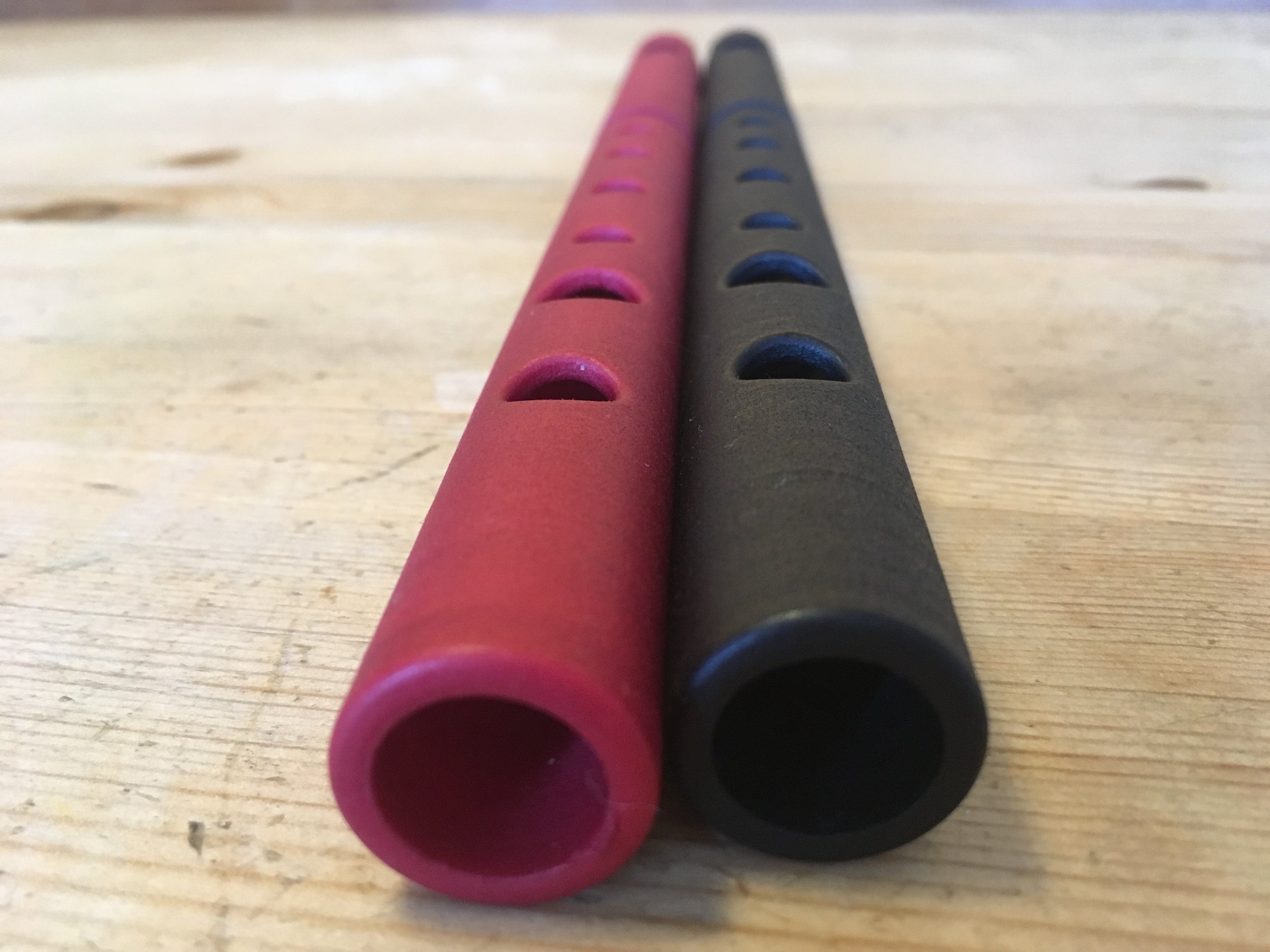 Red and black Qwistle v2.0 instruments on a wooden worktop.